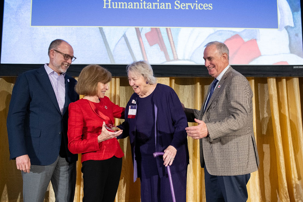 PJ Doyle on stage receives the Presidential Award for Excellence from Red Cross staff members.