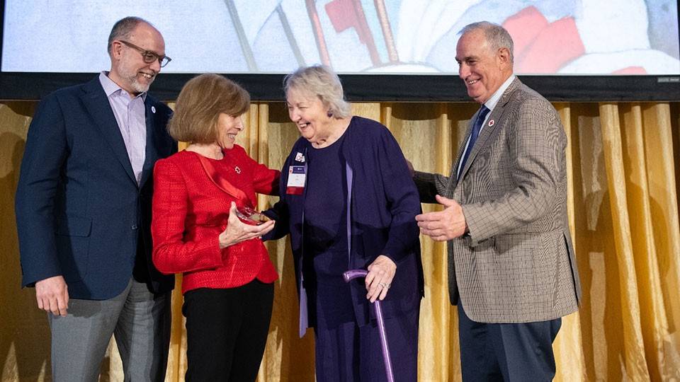 PJ Doyle on stage receives the Presidential Award for Excellence from Red Cross staff members.