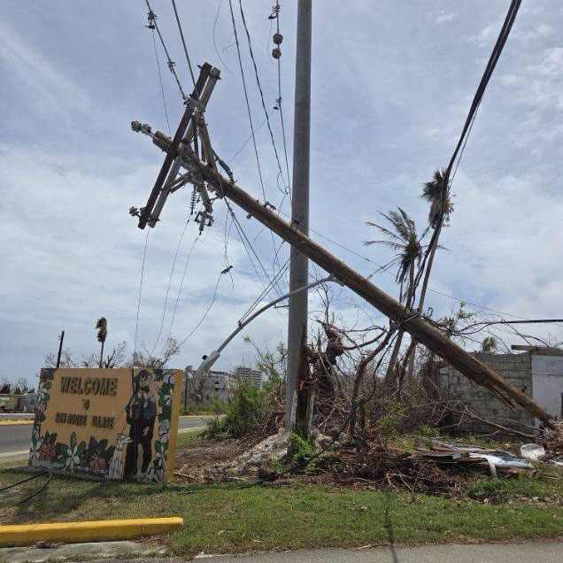a fallen telephone pole next to the side of the street.