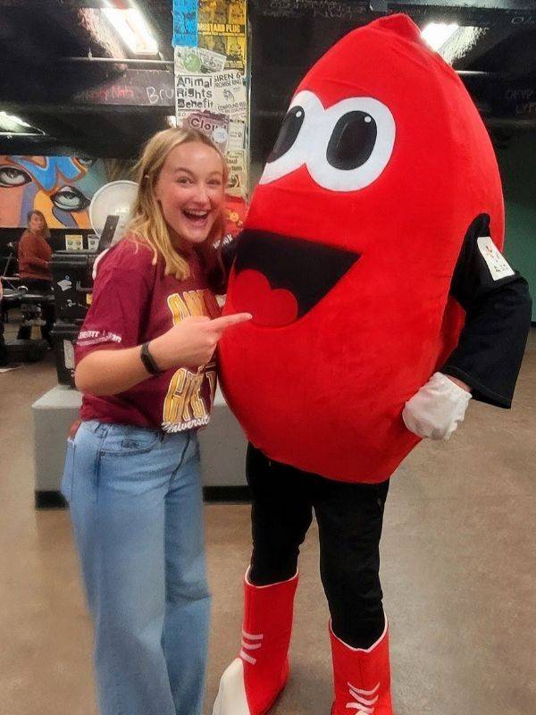 madelyn standing next to blood donor mascot