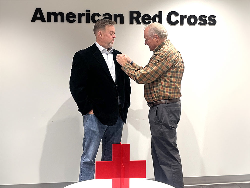 Tom placing a Red Cross pin on Andrew's jacket.
