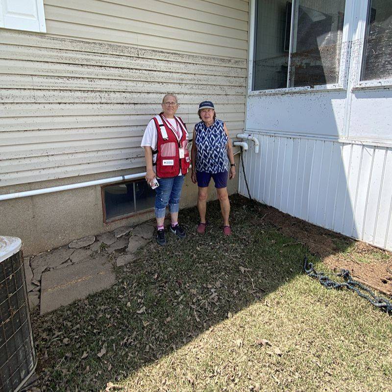 Charlene shows Red Crosser Amanda how high up the floodwaters came and the damage around the home.