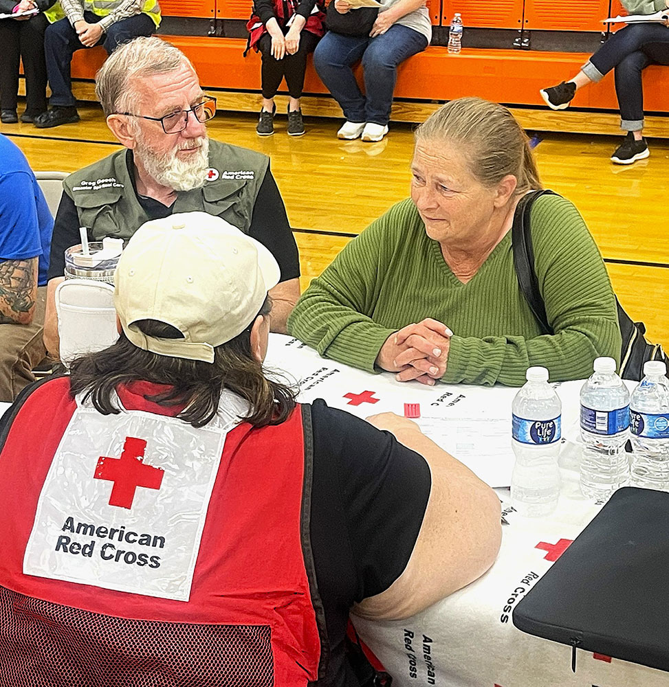 Red Cross volunteers and a person who needs help sitting at a table at a Multi-Agency Resource Center.