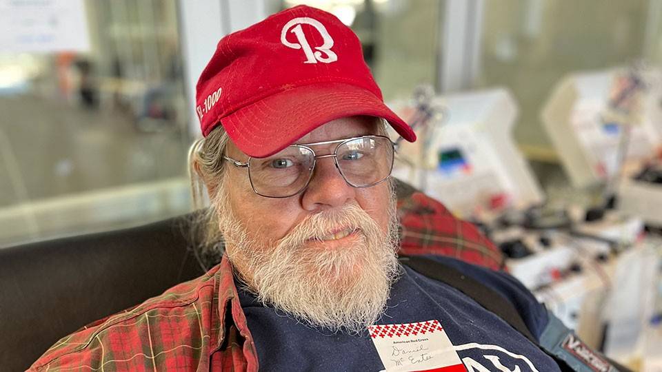 Dan McEntee sitting in chair and donating blood.