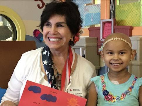Red Cross volunteer next to child in hospital