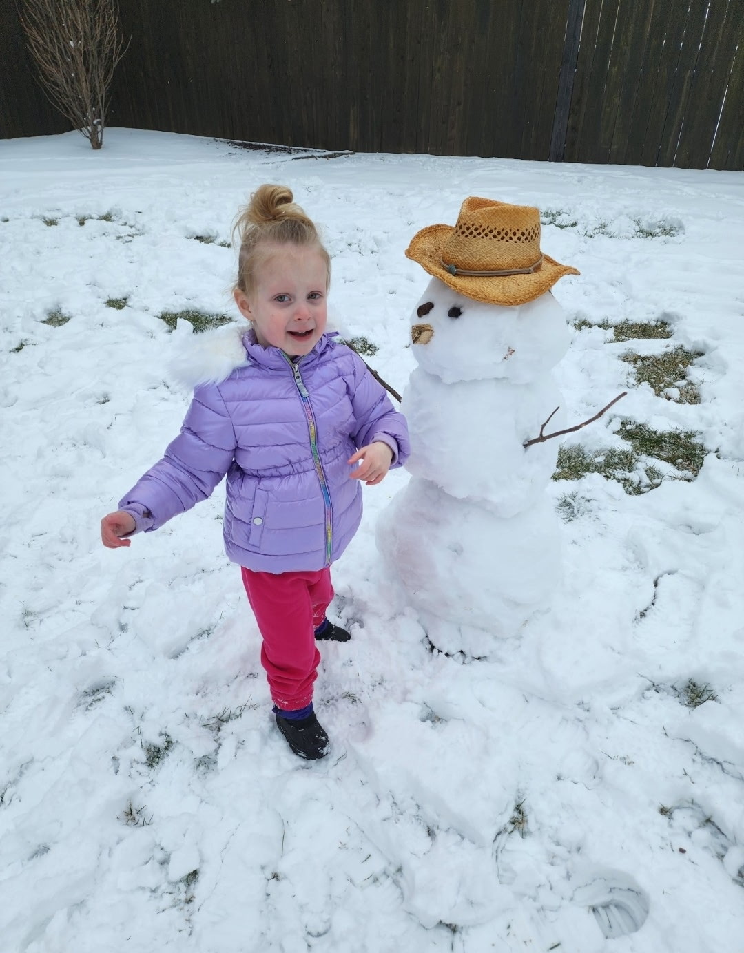 young girl playing in the snow next to snowman