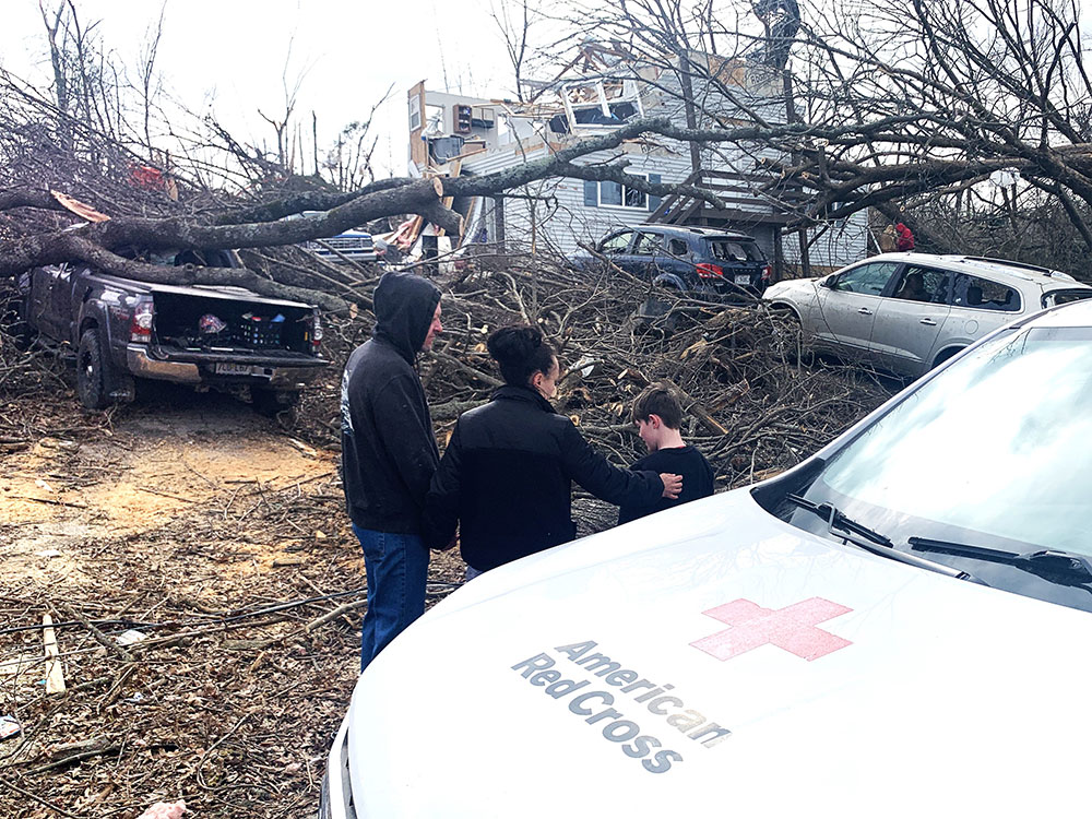 Gregory and Taylor Gerling with son Blake Clark, look at their tornado damaged home.