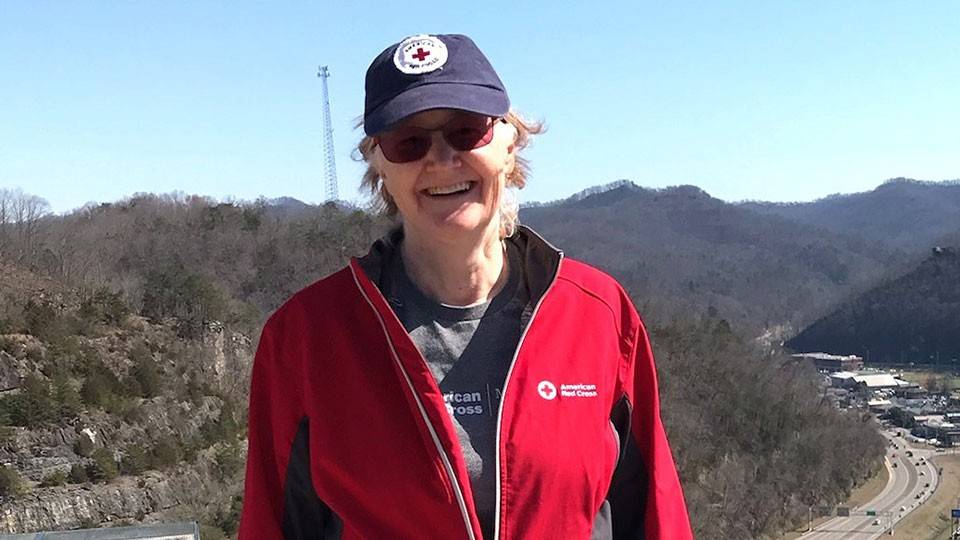 Gwenda Fleming wearing a Red Cross shirt, jacket and hat.