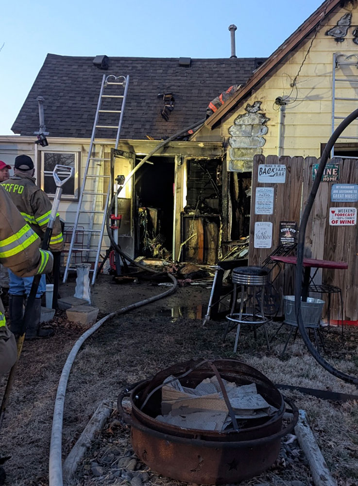 firefighters at a house with fire damage.