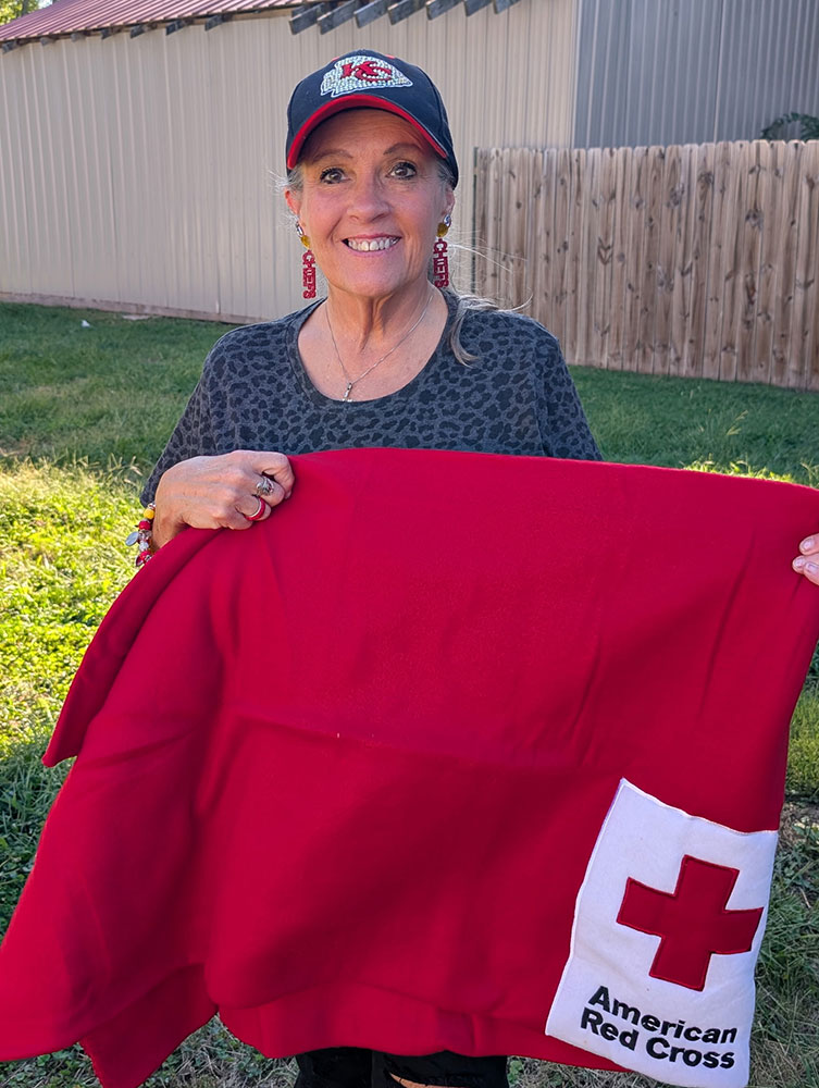 Judy Houseman smiling while holding a Red Cross blanket.