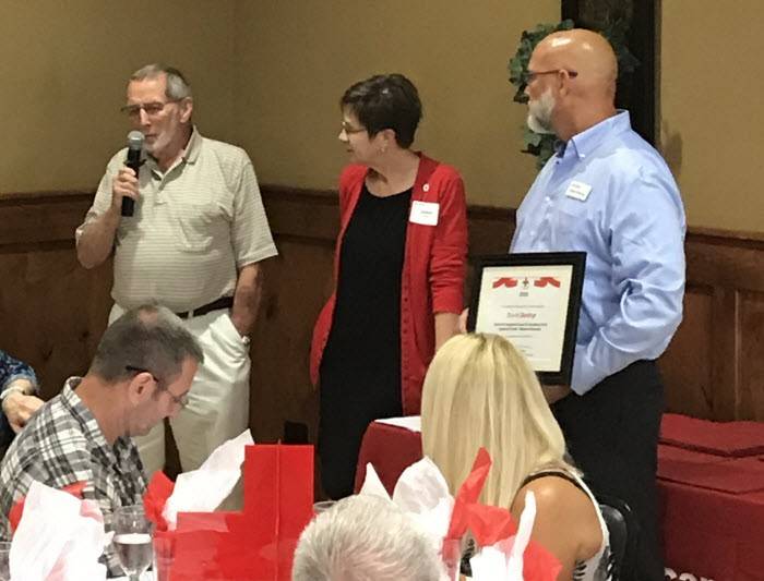 Red Cross volunteer speaking into a microphone while others observe.