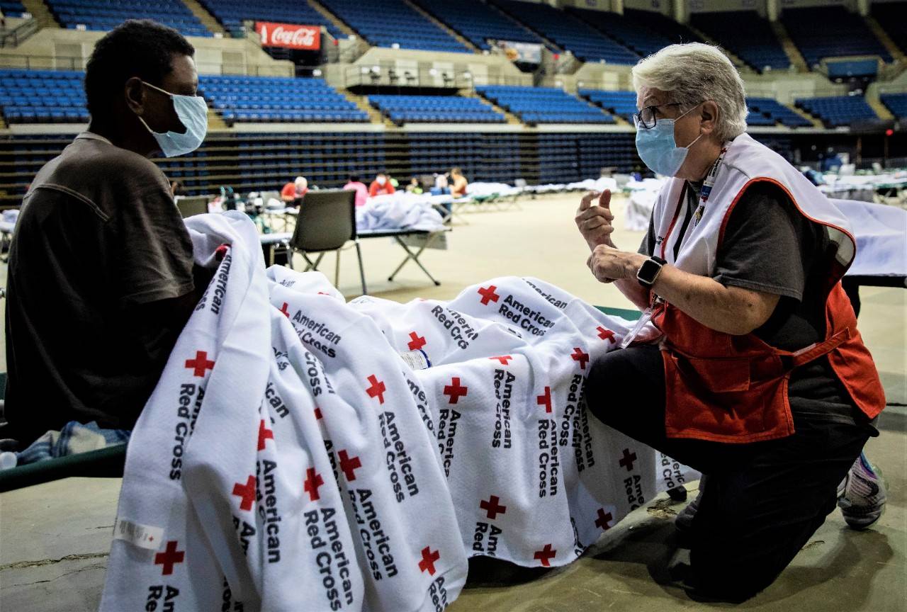 August 31, 2021. Baton Rouge, Louisiana.
Red Cross volunteer Teri Welcher of Minnesota uses American Sign Language to converse with Dianna Morris in a Red Cross shelter in Baton Rouge on August 31, 2021. “I’m happy you’re here and safe,” Teri tells Dianna. Teri is a proud Red Crosser who just finished a deployment to support the wildfire response before pivoting to join the team helping those impacted by Hurricane Ida. Teri learned sign language to communicate with her son and she can sometimes be found serving as an interpreter for deaf blood donors during Red Cross blood drives in Minneapolis.
Photo by Scott Dalton/American Red Cross
