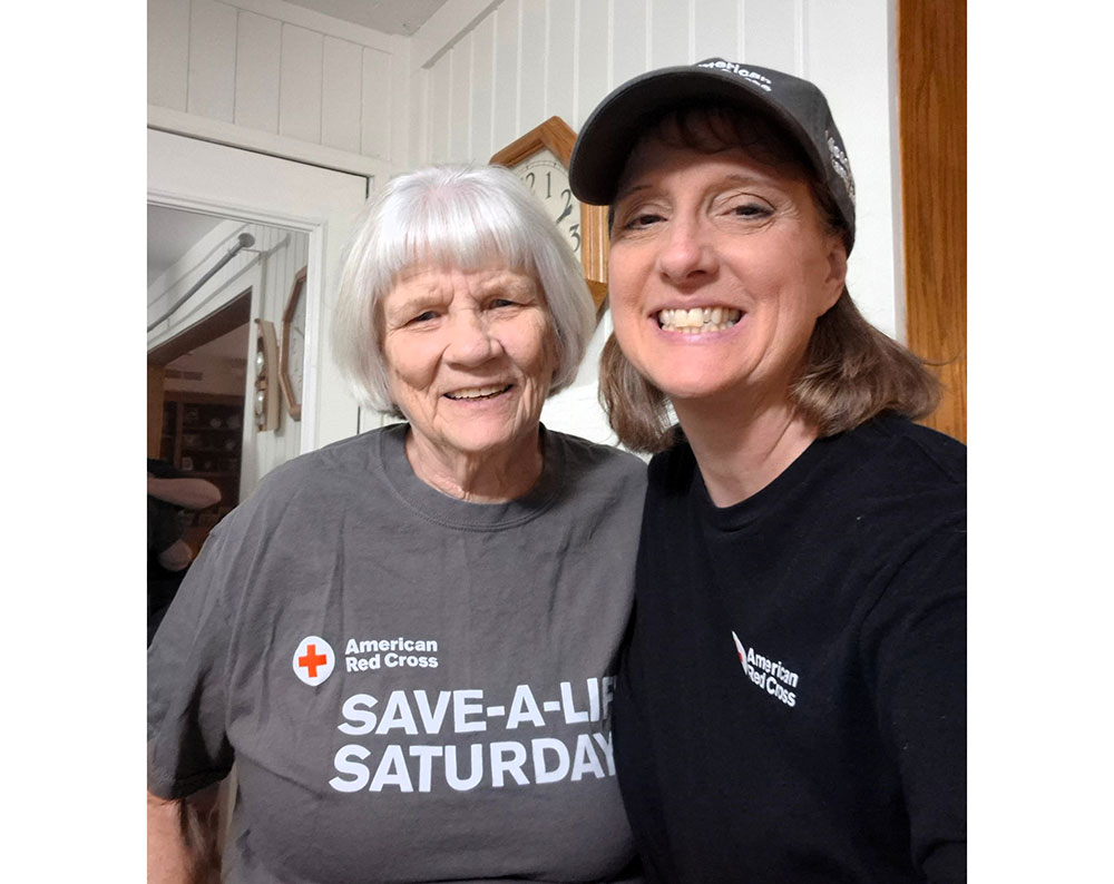 June St. Laurent and her daughter, Denise both wearing Red Cross shirts and smiling.