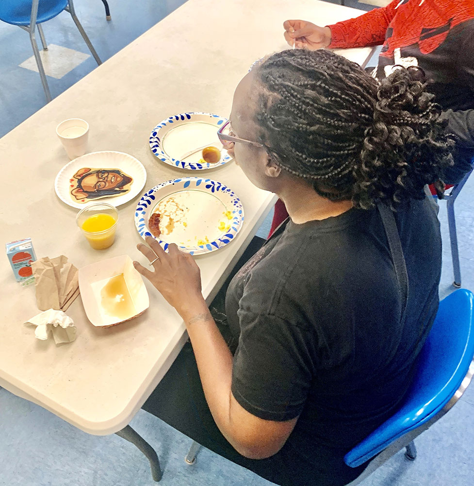 Lacardia Harmon, at a Red Cross shelter, eats breakfast with a pancake portrait of herself.
