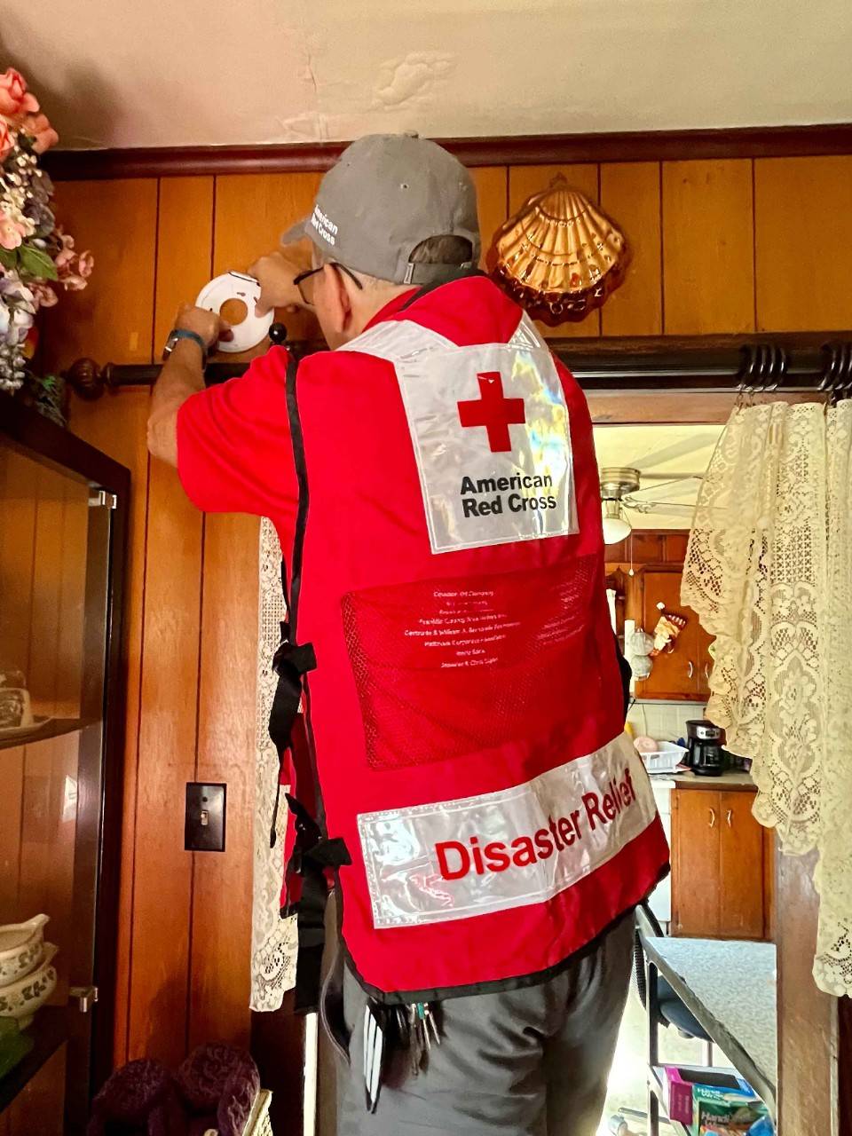 A volunteer hangs a fire alarm.
