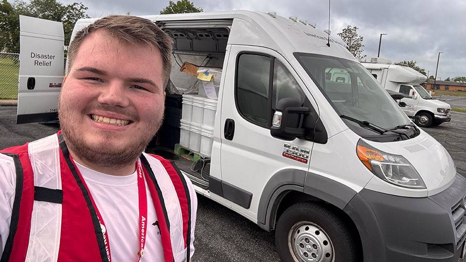 Red Cross volunteer Tyler Gillespie takes a selfie in front of a Red Cross disaster relief van.