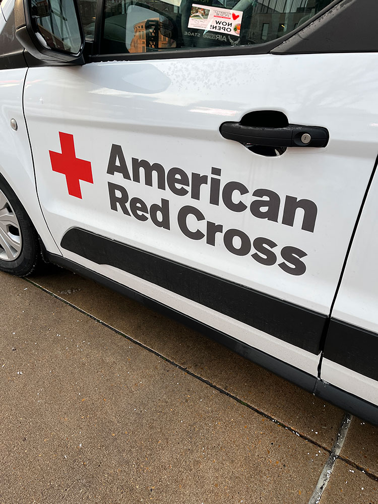 the door of a Red Cross vehicle with the Red Cross logo and name written on it.