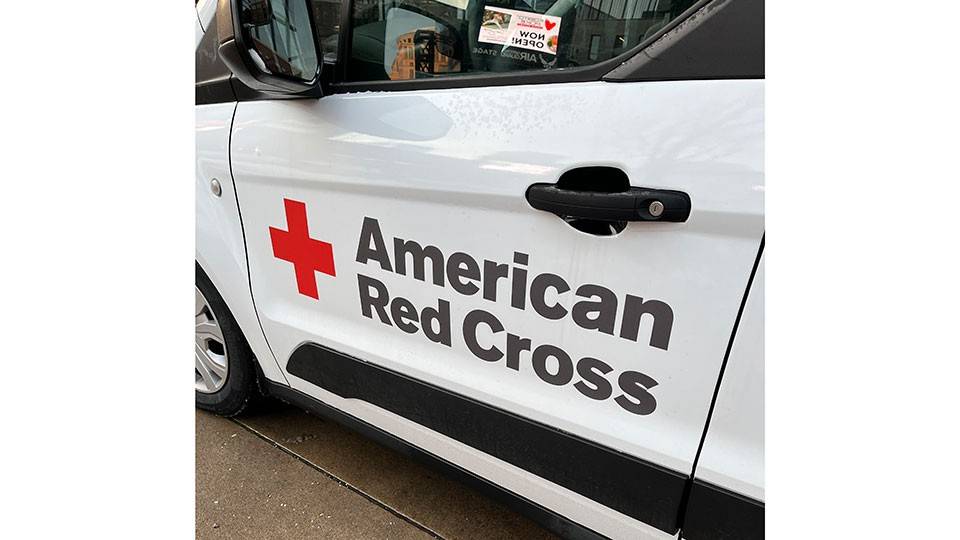 the door of a Red Cross vehicle with the Red Cross logo and name written on it.