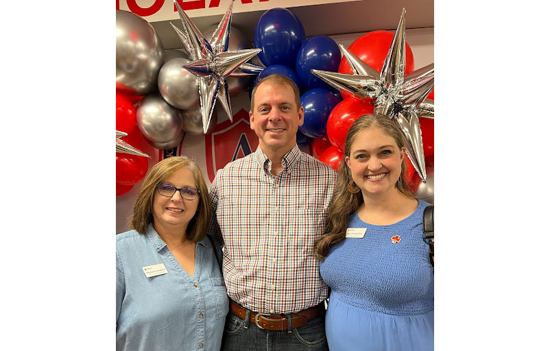 3 people smiling for camera with baloons in background
