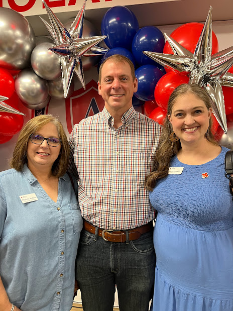 3 people smiling for camera with baloons in background