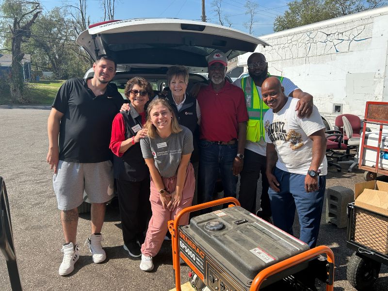 group of red crossers smiling behind back of trunk of vehicle