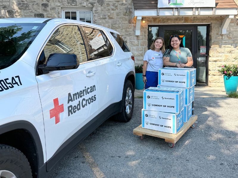 two volunteers standing outside of building with boxes