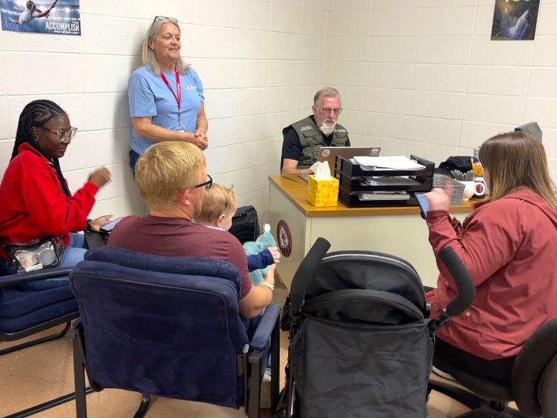 volunteer and other redcrossers with shelter residents sitting around desk.