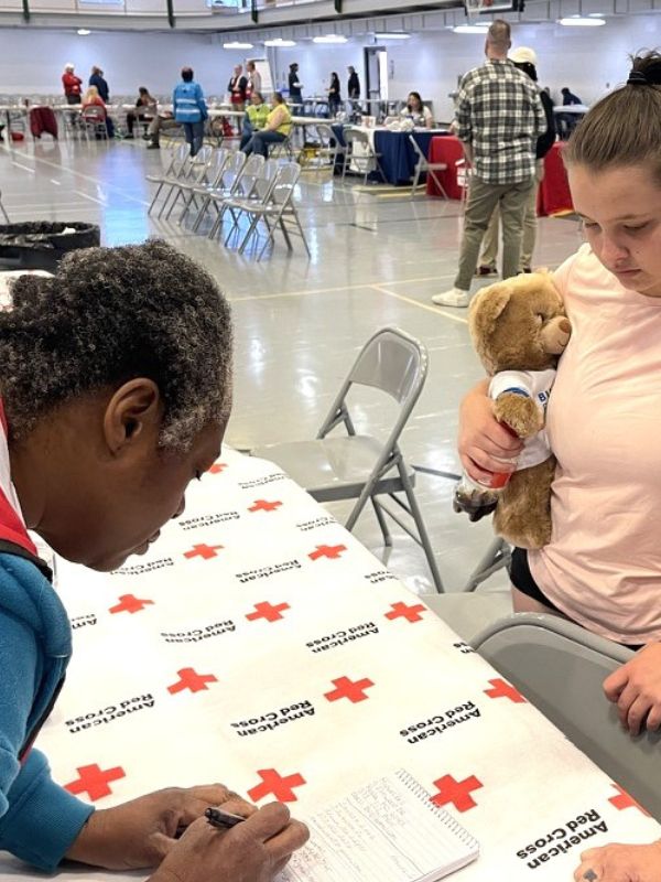 volunteer writing on notepad and speaking with shelter resident.