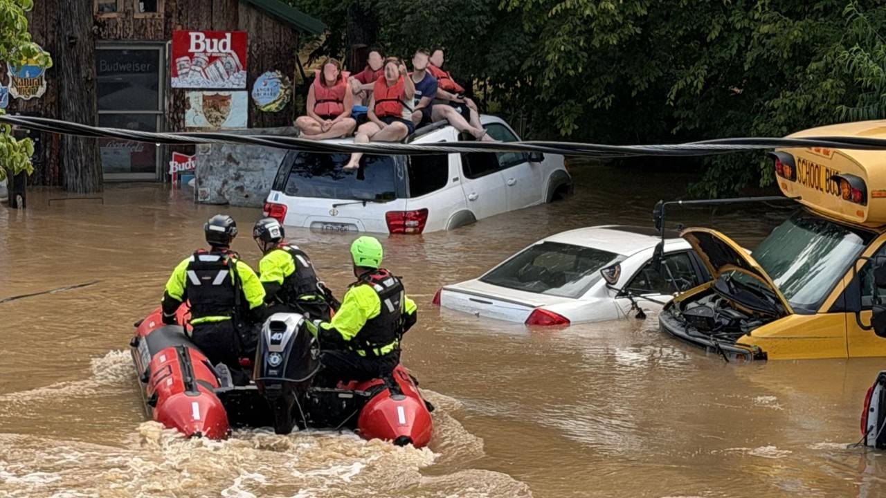 rescuers drive to civilians on top of car in flooded area