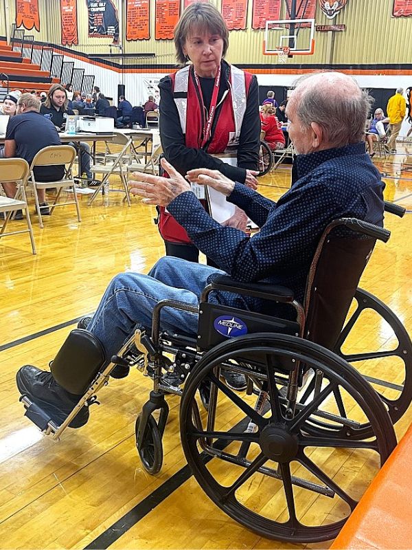 volunteers patsy assisting elder in wheelchair.