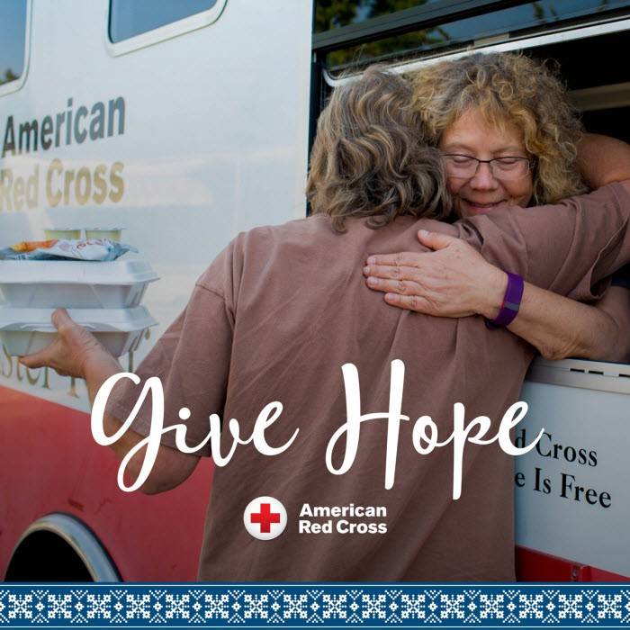 Red Cross volunteer hugging a woman out the window of an emergency response vehicle.