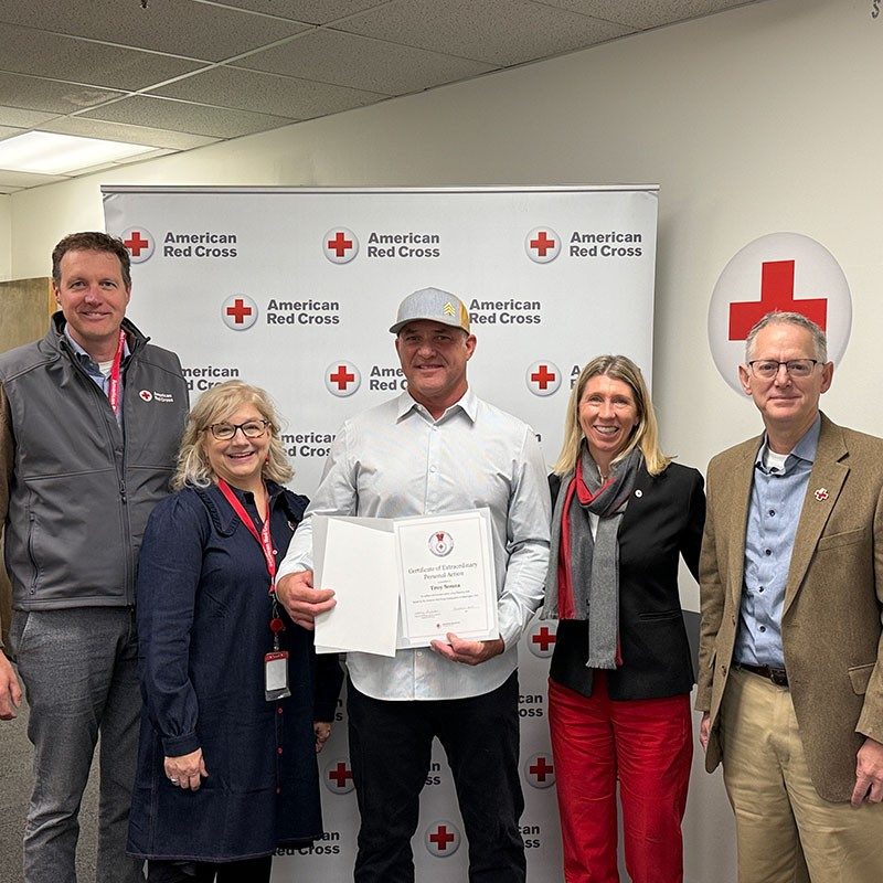 Red Crossers Bryce Sitter, Nicole Sirak Irwin, Vanessa Fry and Andy Marshall present retired firefighter Troy Souza with a Red Cross Lifesaving Award.
