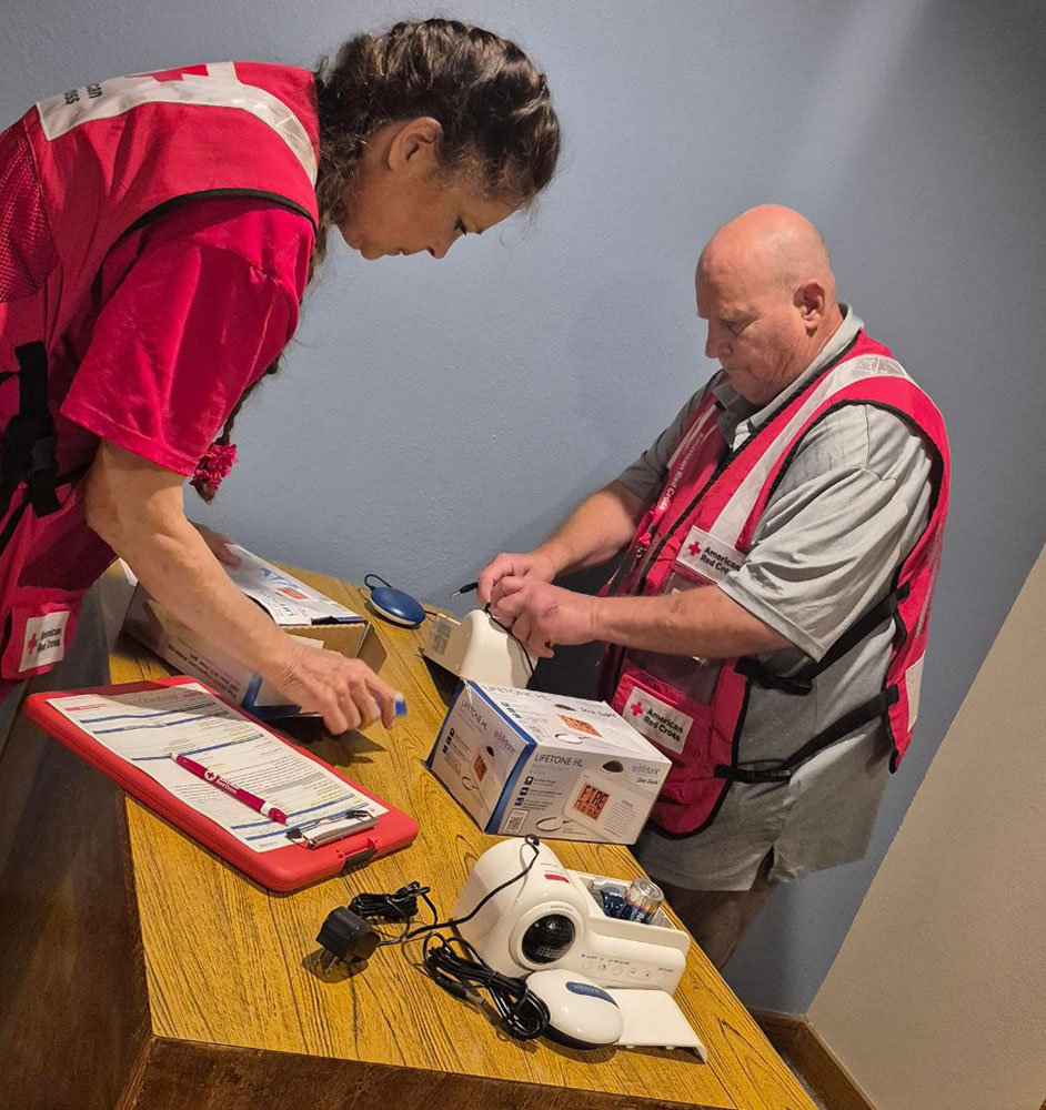 Red Cross volunteers including Rosella Harris and John Albertson install bed-shaker alarms at the Idaho School for the Deaf and the Blind in Gooding. These devices combine a strobe light with a vibrating pad that slips under a mattress or pillow to alert those with hearing challenges when there's a fire.