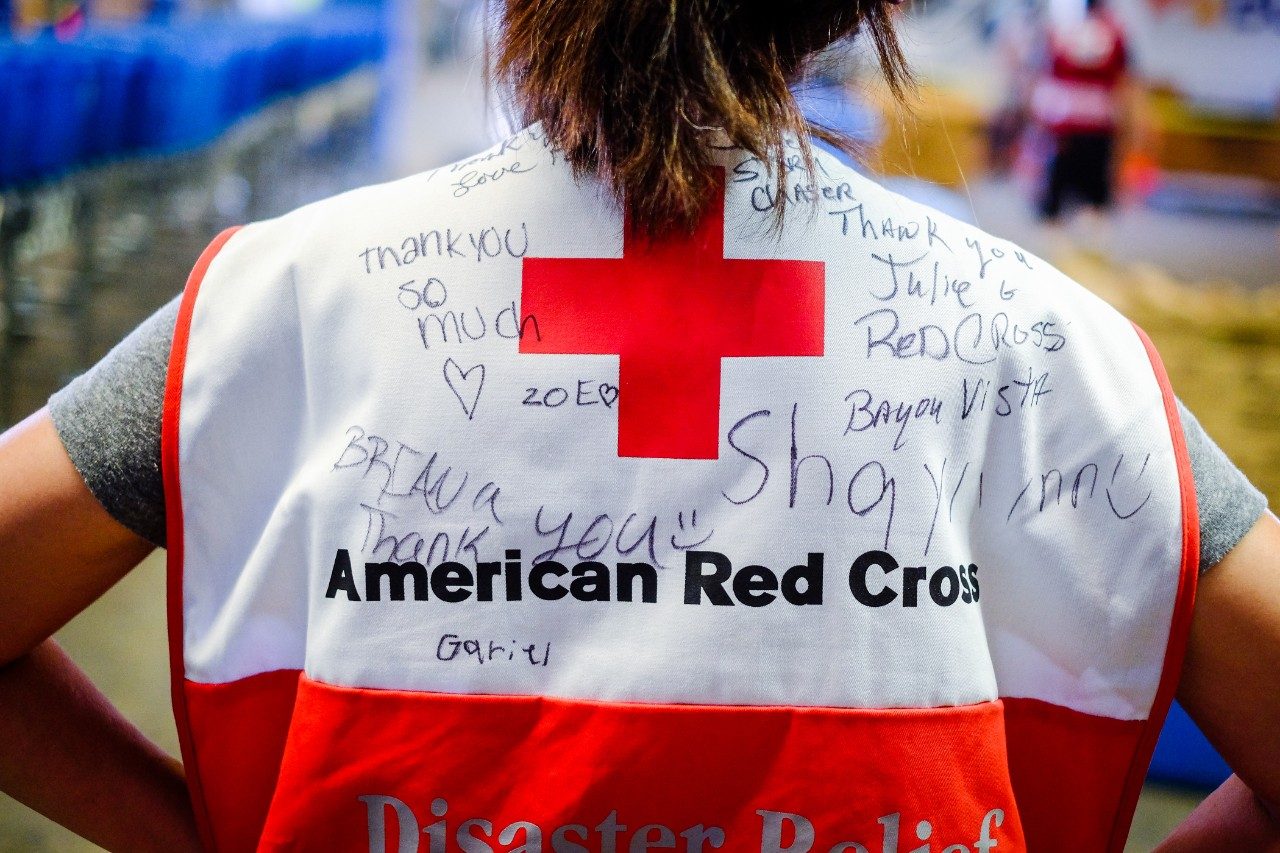 red cross volunteer wearing a disaster vest covered with signatures and hand written thank you messages