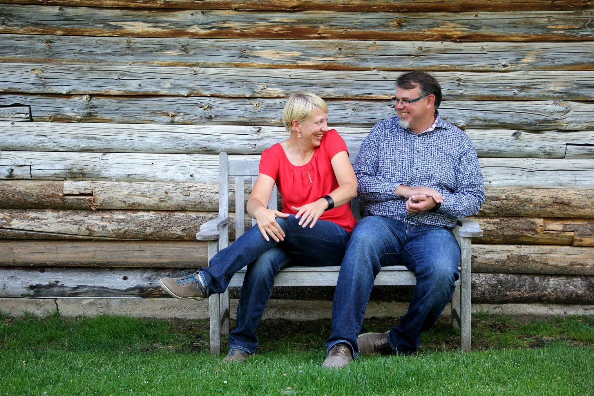 man and woman sitting on bench laughing