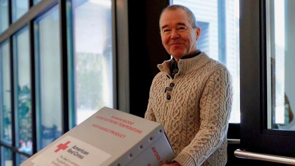 Wolf Ametsbichler smiling while carrying a Red Cross box.
