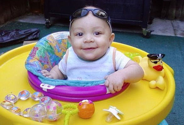 Trayson Harrell as a baby in a walker with toys on it.