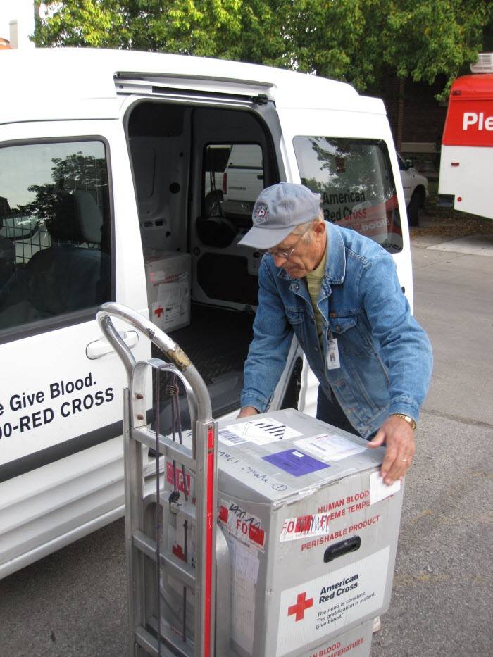 Red Cross blood transportation specialist loading blood products into a Red Cross van.
