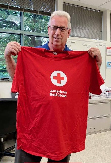 Volunteer Abraham Klippel holds up a Red Cross tshirt
