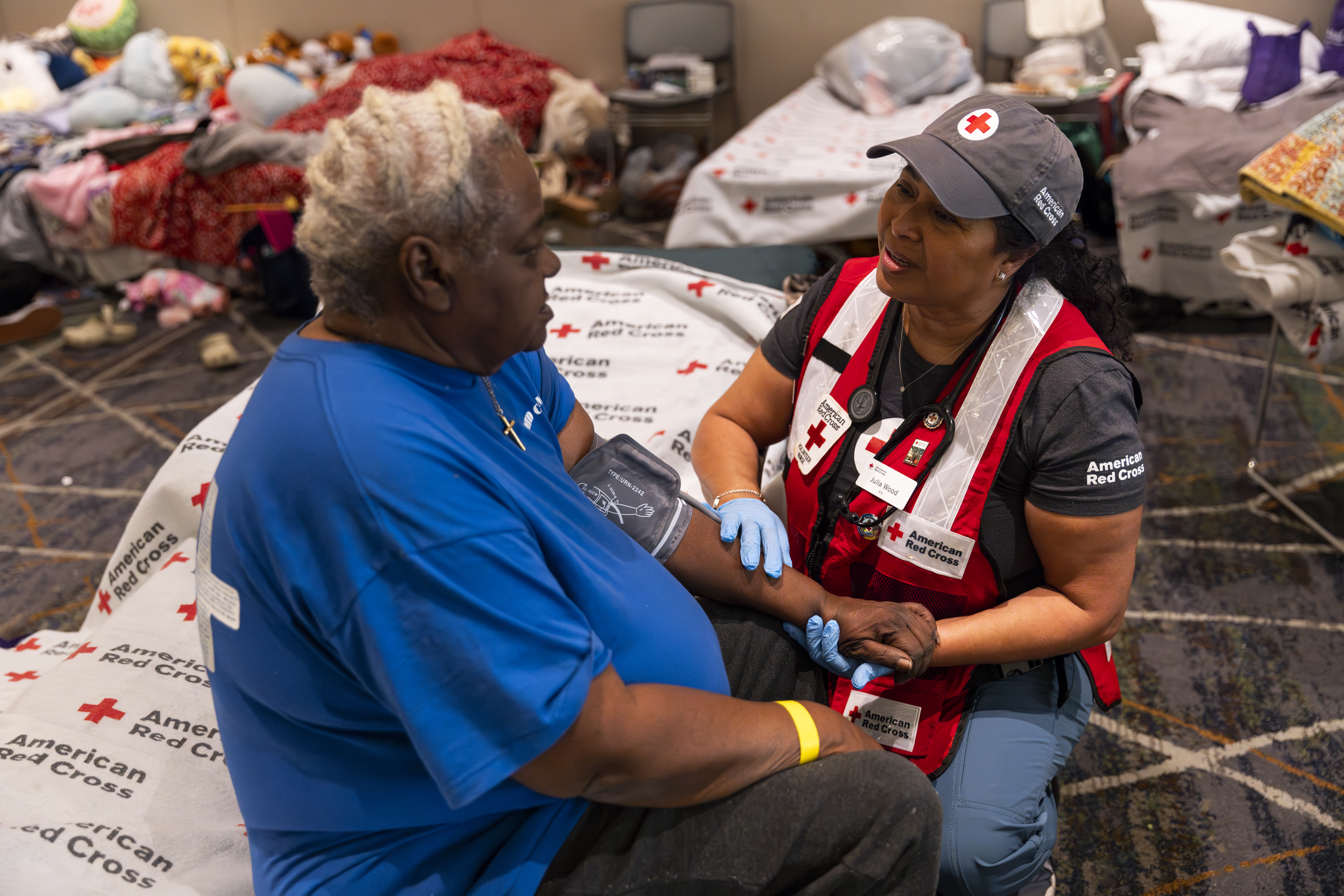 American Red Cross disaster health services volunteer Julin Wood checks the blood pressure of a resident at an emergency evacuation shelter.following the wildfires that swept Los Angeles County. Hundreds of people who were evacuated by the disaster, many of whom lost their homes, are staying there as they navigate their next steps to recovery. Julin paid a visit to the cot of Kay Bailey, who had been evacuated from her home. Red Cross nurses provide critical basic medical support for those affected by disaster, including initial examinations, and often replaces prescriptions and durable medical equipment left behind in the rush to safety.Photo by Scott Dalton/American Red Cross
