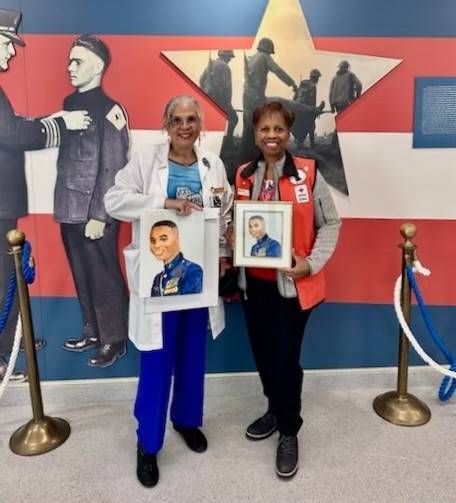 Photograph of two Red Cross volunteers holding a framed painted portrait