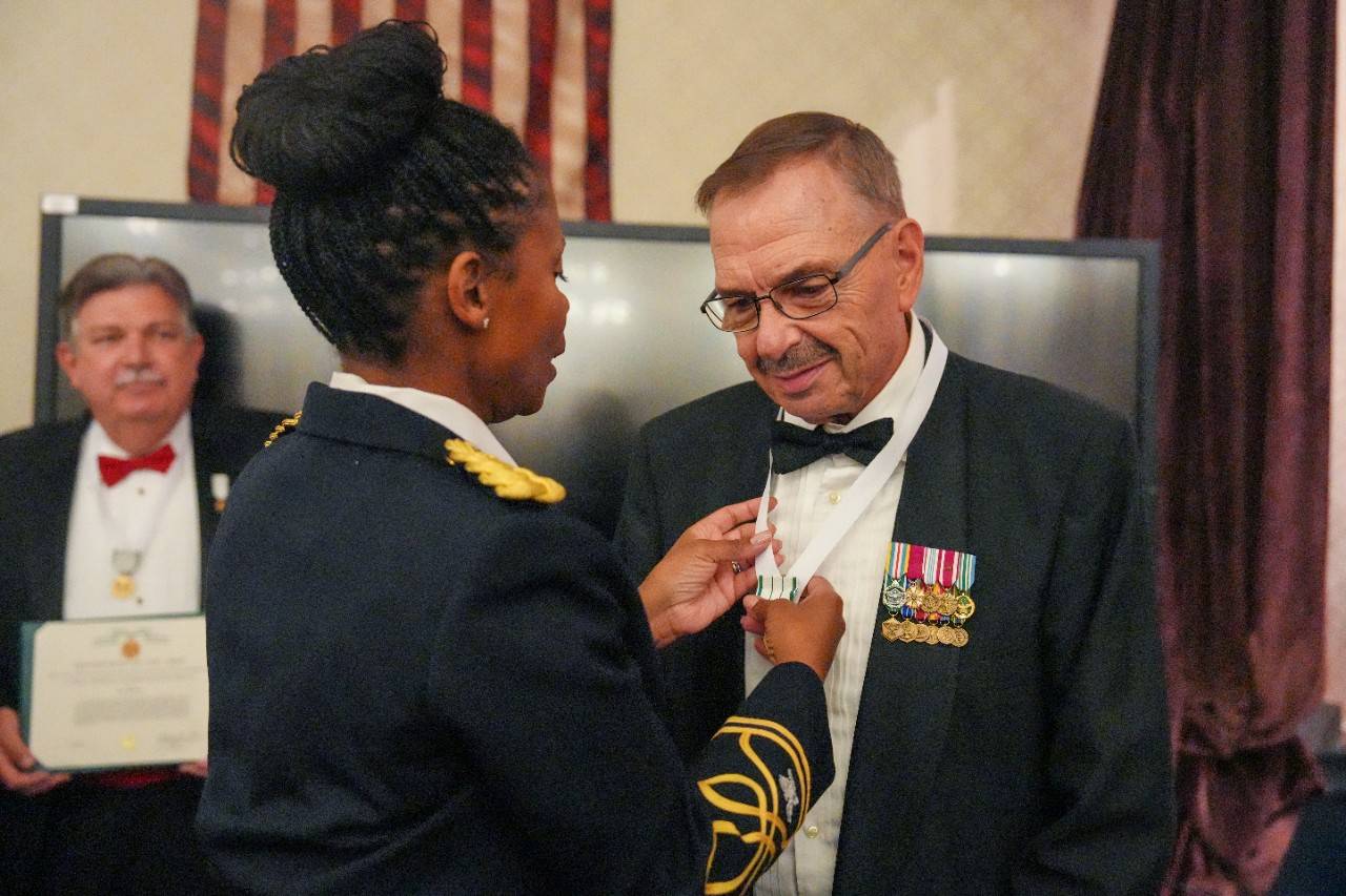Red Cross volunteer James Gilbert receives a ribbon with a medal at an award ceremony at Fort Meade