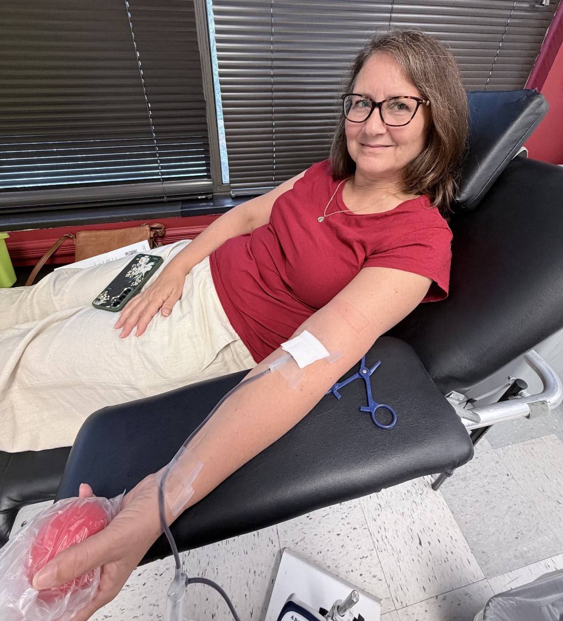 Kristi Giles sitting in a donor chair at the American Red Cross donation center in Columbia Maryland, with a line in her arm, donating blood