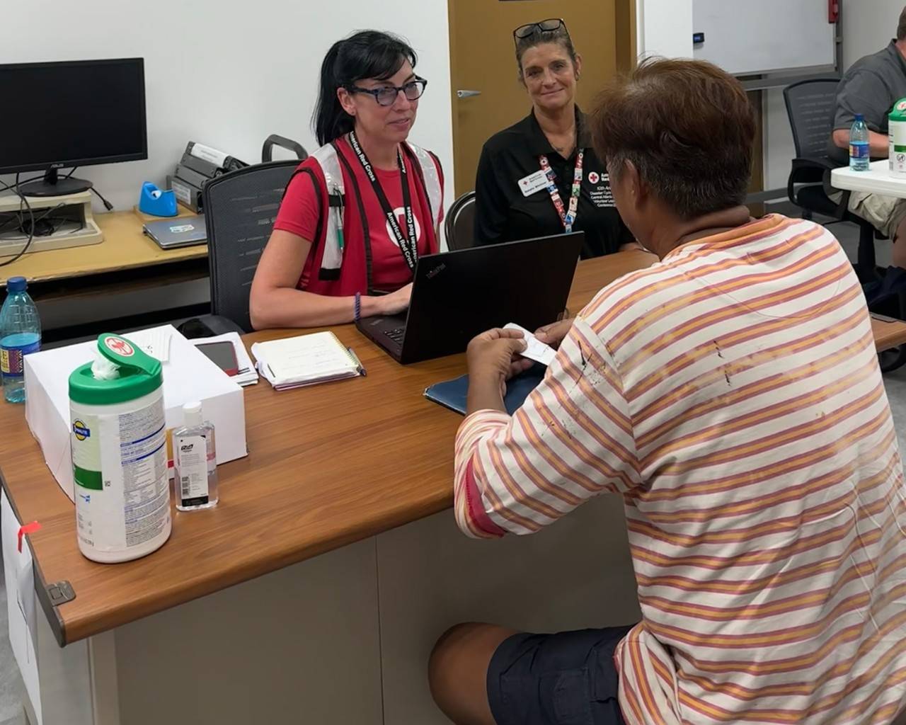 Red Cross volunteers sitting at a desk helping a resident impacted by Typhoon Bavi