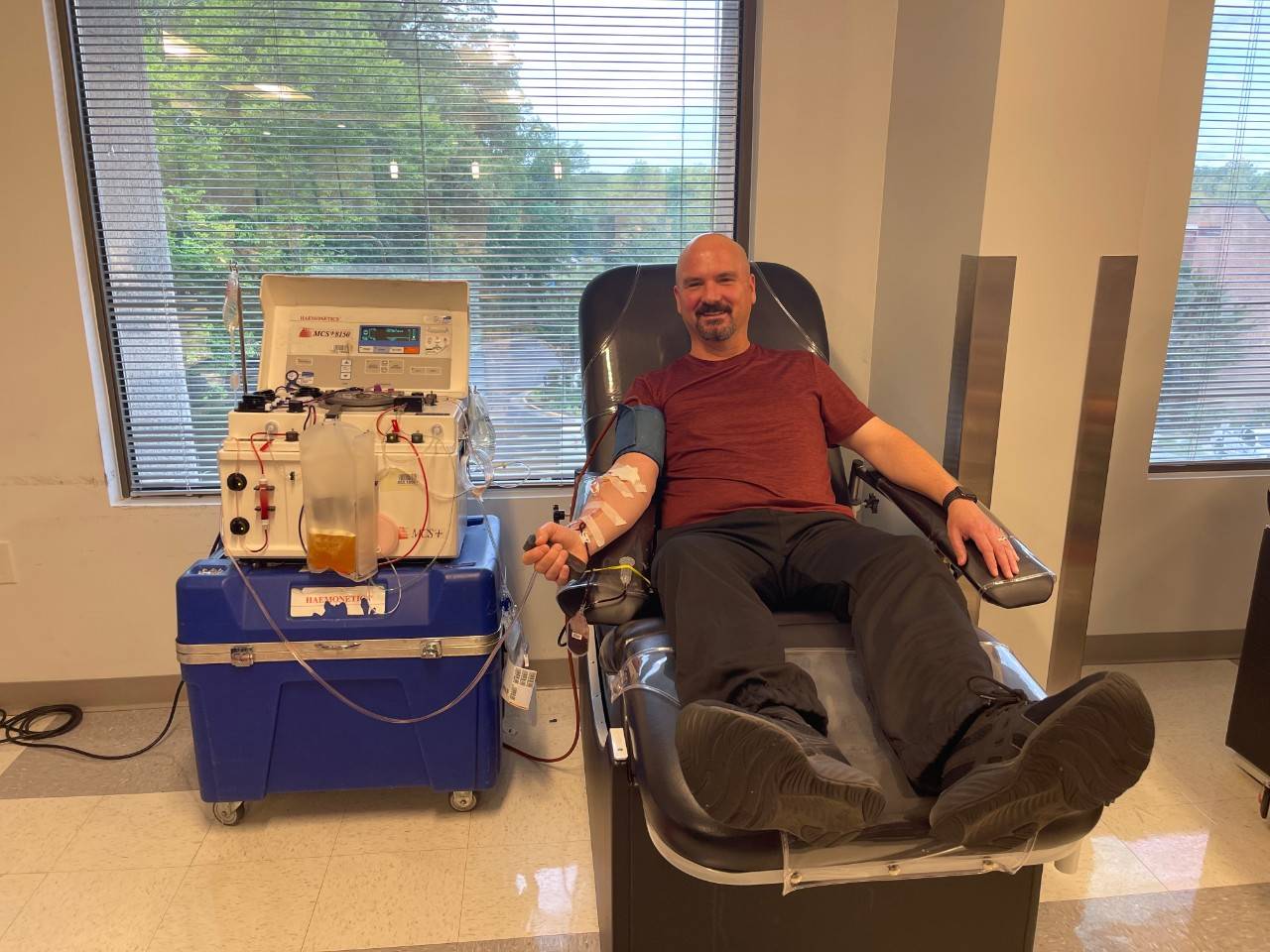 Steve Cribby sits in a donation chair at a Red Cross blood donation center with a line in his arm, donating blood.