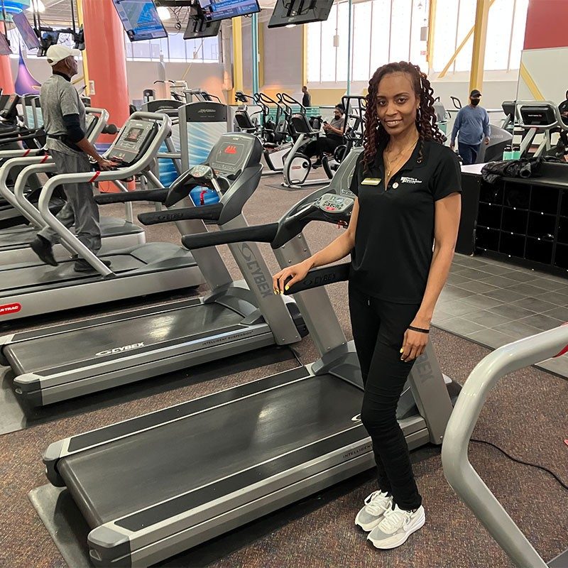 Prince George’s Sports & Learning Complex employee standing next to treadmill