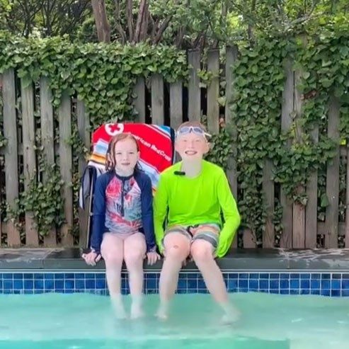 2 kids sitting with feet in pool