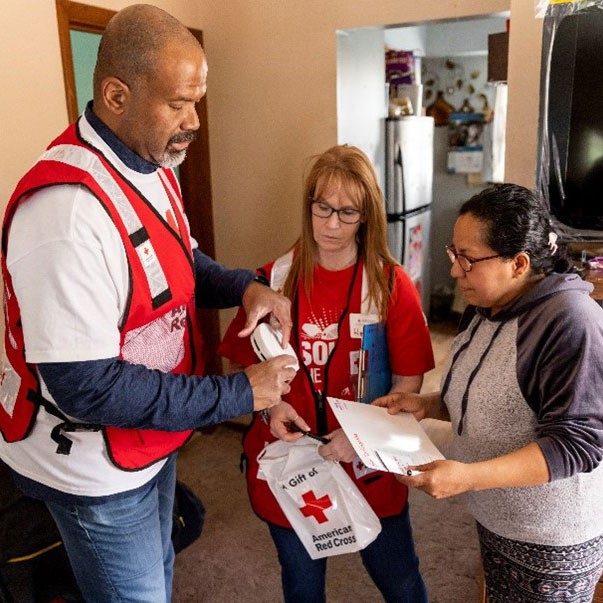 Red Cross volunteers showing lady smoke alarm.