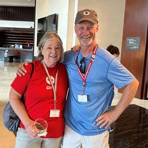 2 Red Cross volunteers smile for camera.