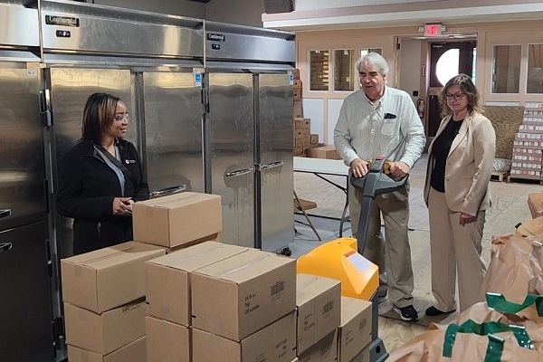 Rosie Taravella and members of the Community Adaptation Program next to pallet jack full of boxes.